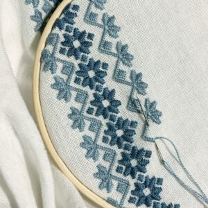 Blue cross-stitch embroidery on natural cotton