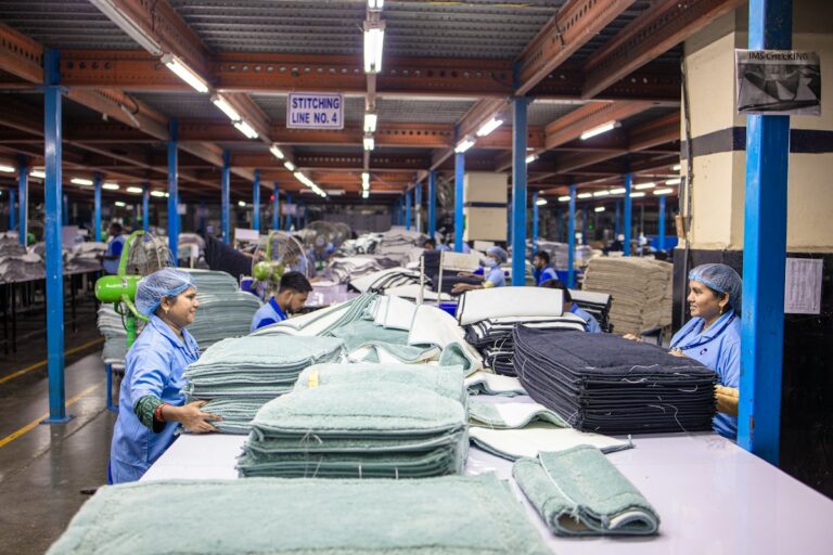 Workers inspecting folded textiles on a factory floor